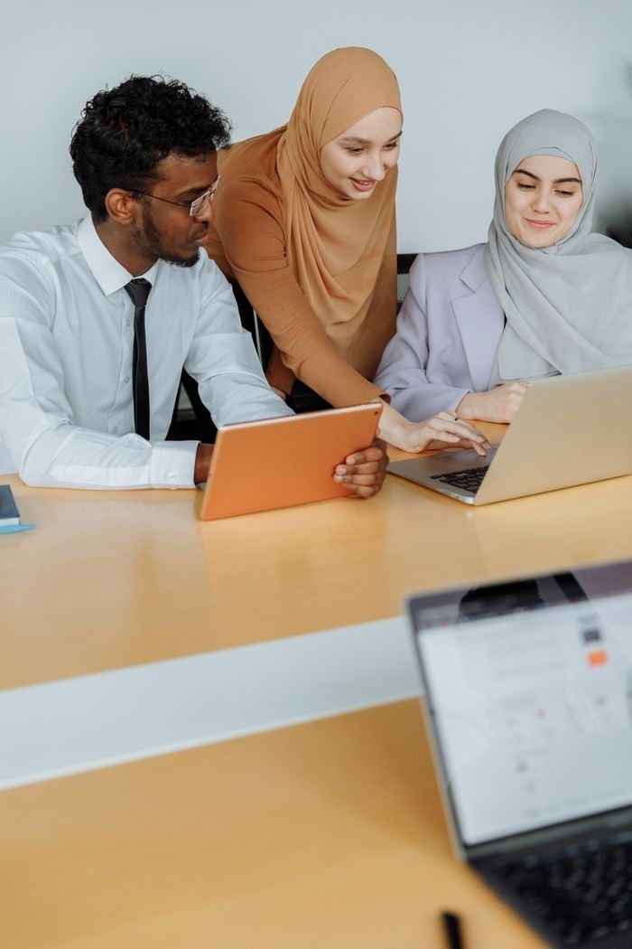 Diverse team working together using laptops and tablets in a modern office setting.